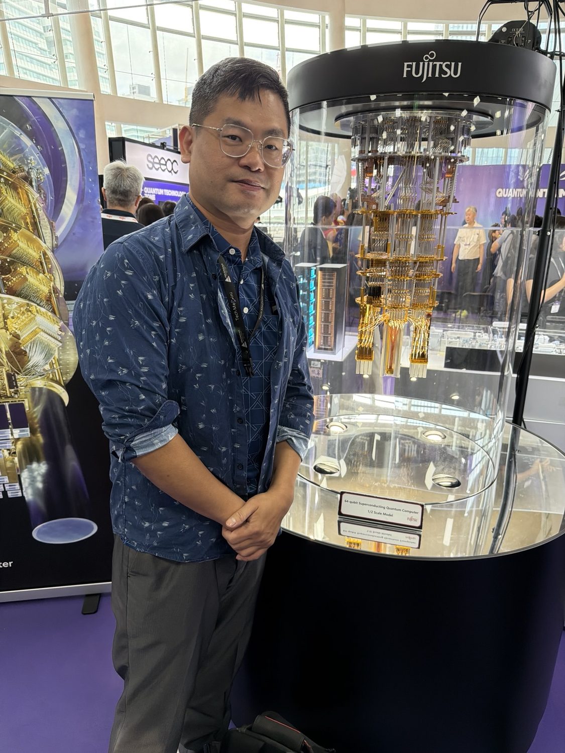 Joel Lin standing beside an exhibited quantum computing system